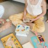 Children and adults playing educational board games in Pakistan with colorful cards, animal puzzles, and geometric wooden pieces, promoting fun and interactive learnin