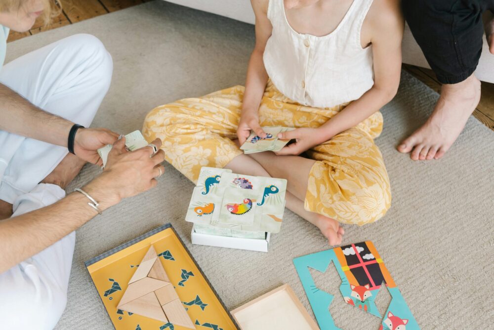 Children and adults playing educational board games in Pakistan with colorful cards, animal puzzles, and geometric wooden pieces, promoting fun and interactive learnin
