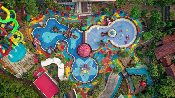 A colorful aerial view of a large water and activity park with multiple slides, splash zones, and play areas surrounded by greenery—illustrating a fun and engaging space that encourages gross motor skill development for children.