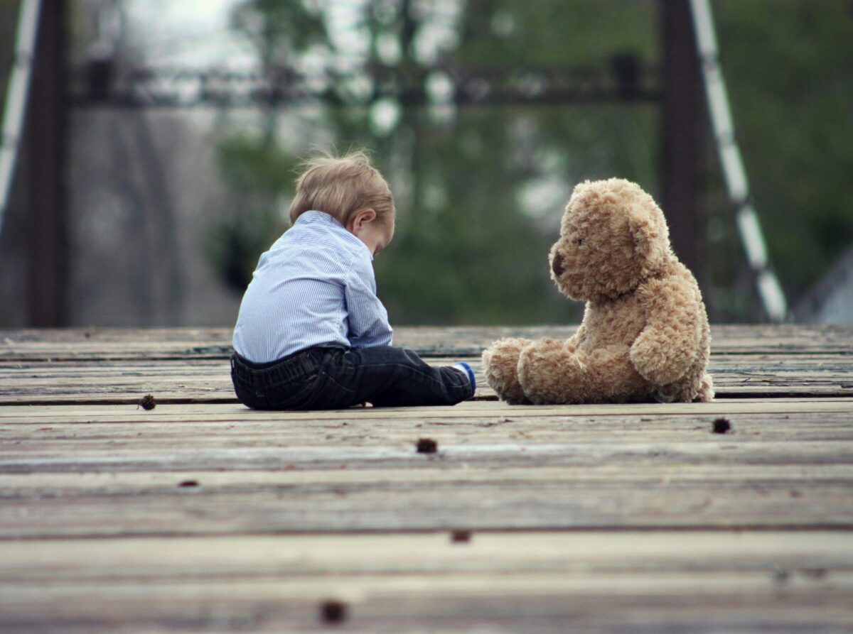 image of a child sitting on road playing with Stuffed Toys in Pakistan